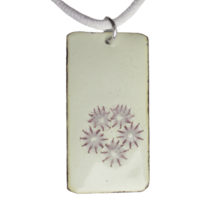 Smaltovaný přívěsek obdélníkového tvaru na ručně opracovaném nerezovém plíšku s drobnými fialovými květinkami na bílém podkladu, zavěšený za kratší stranu na kroužku stříbrné barvy.