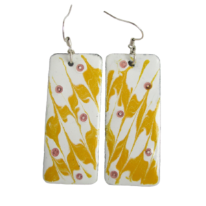 Žlutobílé smaltované náušnice. Náušnice se žlutými a bílými cikcak proužky na ručně opracovaných nerezových proužcích obdélníkového tvaru. Zavěšené za kratší stranu na háčcích stříbrné barvy.