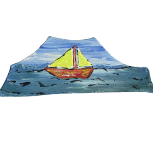 Brož s plachetnicí na moři. Brož nepravidelného tvaru s kresbou plachetnice na vlnách vystřižená z kůže a malovaná modrou, tyrkysovou, hnědou, žlutou, černou a bílou akrylovou barvou. Ze spodní strany je pomocí průhledného plastu připevněný komponent stříbrné barvy.