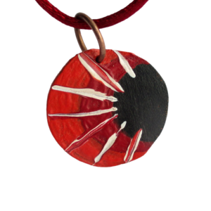 Přívěsek z kůže s bílými paprsky. Přívěsek kruhového tvaru vystřižený z kůže a malovaný černou, červenou a oranžovou akrylovou barvou s bílou kresbou paprsků je zavěšený na bižuterním očku měděné barvy.