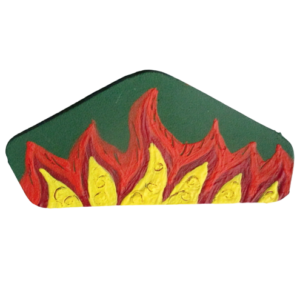 Brož s plameny. Brož ve tvaru nepravidelného pětiúhelníku vystřižená z kůže s kresbou žlutých, červených a oranžových plasticky zdobených plamenů na zeleném pozadí malovaná akrylovou barvou. Ze spodní strany je pomocí průhledného plastu připevněný spínací špendlík stříbrné barvy.