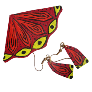 Paví souprava z kůže. Brož ve tvaru kruhové výseče s vlnitým okrajem a náušničky ve tvaru písmene A vystřižené z kůže s černou, oranžovou, žlutou a červenou kresbou akrylovou barvou. Ze spodní strany brože je pomocí průhledného plastu připevněný spínací špendlík stříbrné barvy. Náušnice jsou zavěšené na komponentech zlaté barvy.