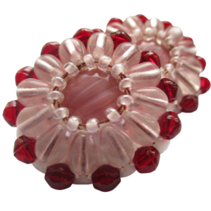 Růžové korálkové puzety. Náušnice vyrobené z růžového jabloneckého knoflíku, které jsou opletené pomocí měděného drátku a korálků v červené a růžové barvě. Jsou podšité bílou plstí. Ze spodní strany jsou pomocí průhledného plastu komponenty ve stříbrné barvě.