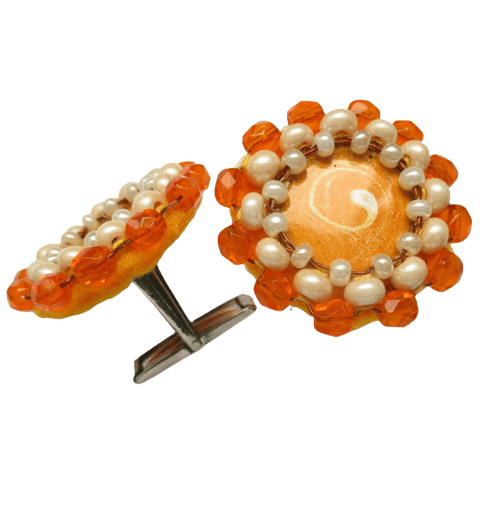 Manžetové knoflíčky béžové a oranžové barvy se středem ze smaltovaného nerezového plíšku orámované skleněnými korálky. Spodní strana je podšitá žlutou plstí.