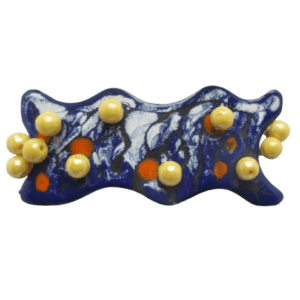 Smaltovaná spona s bílou, modrou, černou a oranžovou kresbou s motivem soumraku, doplněná pastelově žlutými skleněnými knoflíky. Základový plíšek je lehce prohnutý a ručně opracovaný do nepravidelného tvaru. Vespod je pevným vlascem uchycená francouzská spona délky 6 cm.