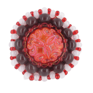 Červenohnědá korálková brož. Brož vyrobená z červeného jabloneckého knoflíku, který je opletený pomocí měděného drátku a korálků v červené, hnědé a bílé barvě. Je podšitá červenou plstí. Ze spodní strany je přišitý špendlík ve stříbrné barvě.