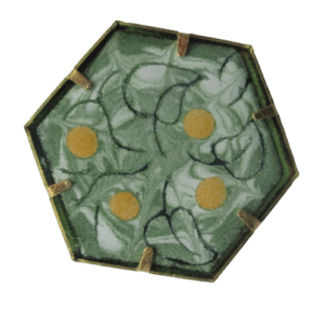 Zelenkavá smaltovaná brož. Brož šestiúhelníkového tvaru s černou kresbou lístků a žlutými puntíky na zelenkavém podkladu na ručně opracovaném nerezovém plíšku. Plíšky jsou mechanicky uchycené v bižuterním lůžku. Brožový můstek je připevněný nýty. Komponenty jsou ve zlaté barvě.