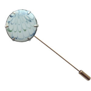 Světlá smaltovaná jehlice do klopy. Hodí se k tmavému saku s bílou košilí. Můžete ji doplnit manžetovými koflíčky se stejnou kresbou.