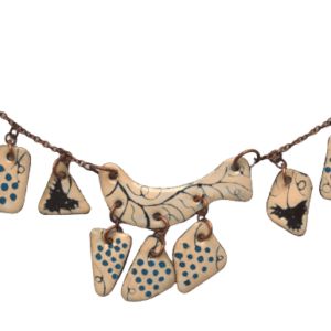 Smaltovaný náhrdelník s modrými vinnými hrozny z kolekce inspirované krojem mělnického folklórního souboru. Hodí se pro slavnostní příležitosti. Je navržený k nošení na kratší šňůrce nad hranou výstřihu. Doplňte jej náušnicemi nebo broží ze stejné kolekce.