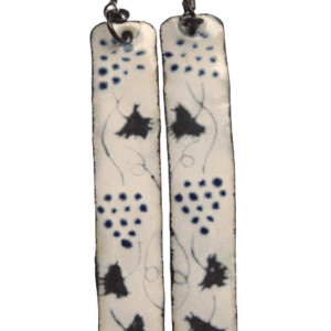 Smaltované náušnice s černými vinnými hrozny. Smalty obdélníkového tvaru na ručně opracovaných nerezových plíšcích s černou a modrou kresbou vinných hroznů a listů na bílém podkladu. Jsou zavěšené za kratší stranu na háčcích černé barvy.