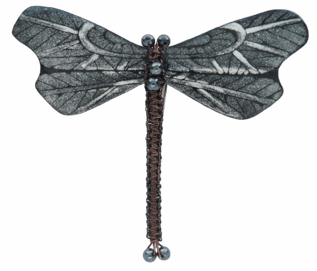 Smaltovaná černobílá vážka. Elegantní a výrazná brož ve tvaru vážky, která oživí váš outfit. Křídla jsou ručně smaltovaná v černobílém provedení, zatímco tělo je pečlivě drhané z měděného drátku a skleněných korálků. Skvěle se hodí na šaty, kabát nebo sako, kde vynikne její jedinečný design. Brož je součástí větší kolekce – dokonale ji zkombinujete s korálkovými, drhanými i smaltovanými náušnicemi pro dokonalý stylový celek.