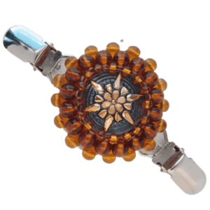 Hnědozlatá korálková oděvní spona s šedým skleněným knoflíkem se zlatým reliéfem květiny.